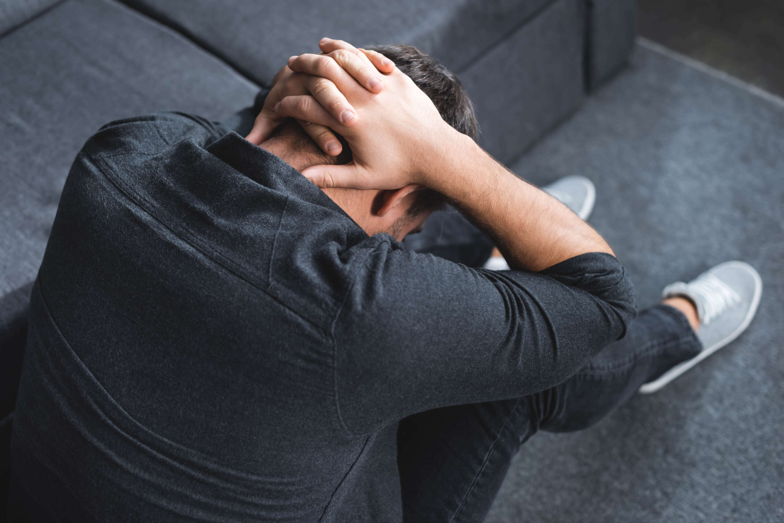 high angle view of man with headache touching head in apartment
